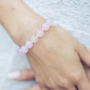 Close-up of translucent pink sunstone beaded bracelet worn on a woman's wrist