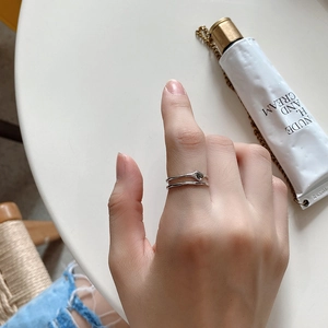 Close-up of minimalist double-layered silver ring on hand with elegant marble background