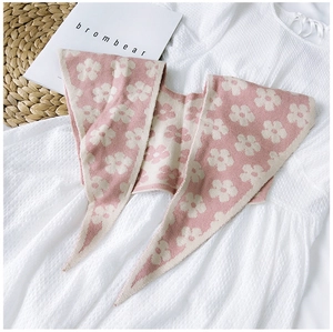 Detail of pink knitted flower shawl scarf laid on a woven mat with decorative books