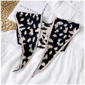 Detail of a black and white leopard print knitted shawl scarf styled over a white dress