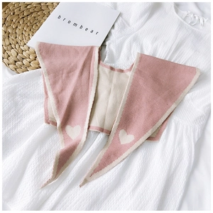 Detail of pink and beige knitted shawl with white heart pattern on white dress