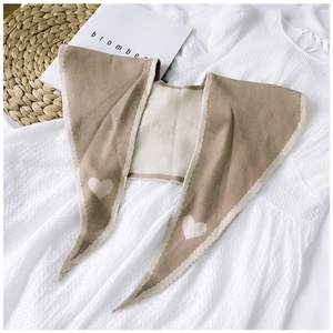 Flat lay of a beige and white knitted shawl with heart pattern on a textured dress