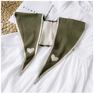 Detail view of army green knitted shawl wrap with cream heart patterns and white piping