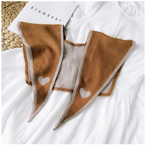 Flat lay of brown knitted shawl with beige heart patterns on white dress background