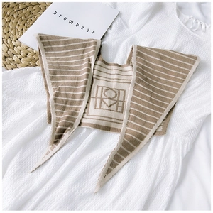 Detailed knit texture of striped khaki shawl on waffle dress with elegant logo accent
