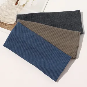 Close-up of ribbed knit yoga headbands in dark grey, tan, and navy blue fabric textures