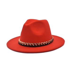 Detail of red wool fedora featuring a bold gold metal chain and black leather trim