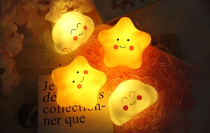 Close-up of cute smiling star and cloud night lights with warm glow on decorative tray