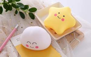 Close-up of cute star and cloud night lights with cartoon faces on soft gauze background