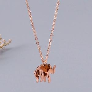 Detail view of a rose gold elephant pendant necklace on a delicate metal cross chain