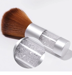 Close-up of nail dust brush with crystals in transparent handle and soft brown bristles