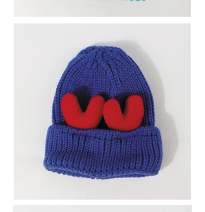 Detailed macro view of royal blue knit beanie featuring plush red heart accents on top