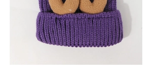 Close-up of thick purple knit texture and brown decorative antlers on a warm beanie