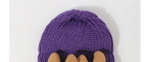 Macro shot of thick purple knit beanie showing chunky yarn texture and brown plush decor