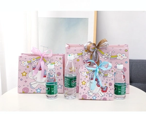 Three sizes of pink unicorn gift bags with satin bows shown next to a water bottle
