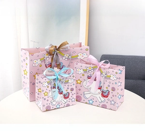 Pink unicorn gift bags with satin bows and handles in three different sizes on a white table