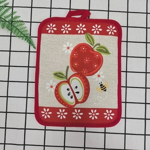 Detail of red cotton baking mat with apple pattern and hanging loop on grid background