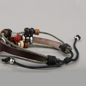 Detail of woven leather bracelet with wooden beads and turquoise eye charm on grey background
