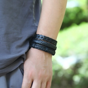 Close-up of black braided leather bracelets with various textures on a model's wrist
