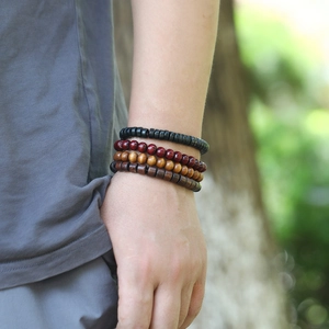 Close-up of a stacked set of four wooden beaded bracelets in brown and black on a wrist