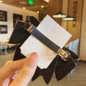 Elegant black velvet bow hair clip with a non-slip metal spring fastener on a card