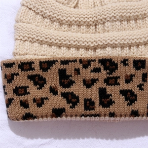 Macro shot of chunky knit texture and leopard print cuff on a beige winter beanie