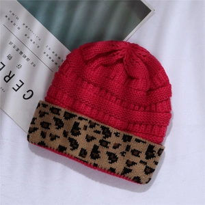 Detail of fuchsia knit beanie with leopard print cuff on a minimalist white background
