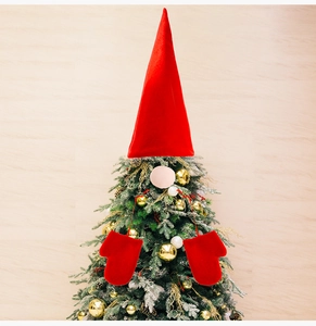 Close-up of red velvet gnome tree topper with long hat, nose and gloves on a tree