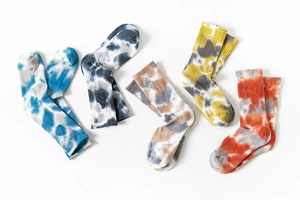Detail showing five pairs of colorful tie-dye crew socks with ribbed texture in a flat lay