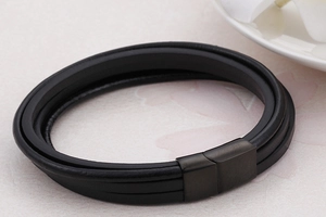Detail of multi-layer black leather bracelet featuring a matte black magnetic clasp close-up