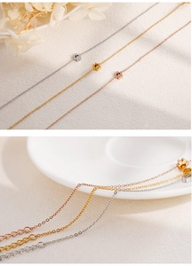 Dettaglio di tre delicate collane con ciondolo a fiore in argento, oro e oro rosa
