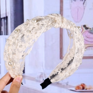 Détail du serre-tête en dentelle crème avec broderie florale et perles blanches