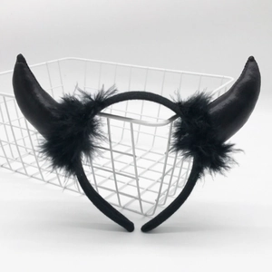 Detail of a black devil horn headband with soft feather accents in a white basket