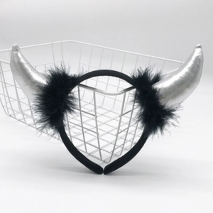 Detail of a black headband with silver horn decorations and feather accents on top