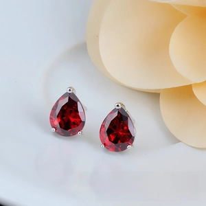 Detail of pear-cut dark red zircon stud earrings with silver three-prong setting
