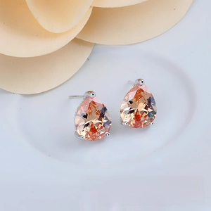 Detail of champagne teardrop zircon earrings with silver three-prong setting on plate