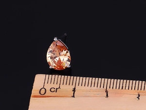 Detailed macro view of 10mm orange pear-cut zircon stud earring with silver claw setting