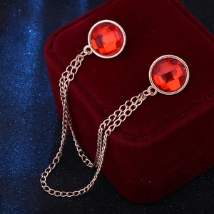 Detail of gold collar pin with red faceted stones and double chains on velvet box
