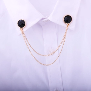 Close-up of double-layer gold chain collar pin with black faceted gemstone on a white shirt