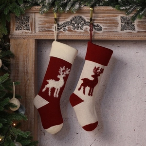 Knitted Christmas stockings with reindeer pattern hanging on a festive mantelpiece