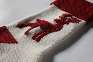 Close-up of knitted Christmas stocking with reindeer pattern showing wool texture