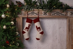 Close-up of knit Christmas stockings with reindeer patterns hanging on a fireplace