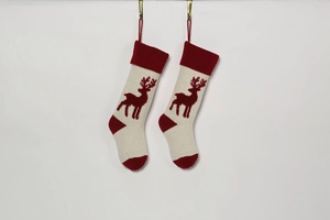 Close-up of knitted Christmas stockings with red reindeer patterns on a clean wall