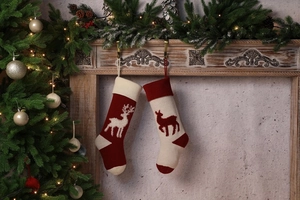 Close-up of knitted Christmas stockings with reindeer patterns on a wooden mantel