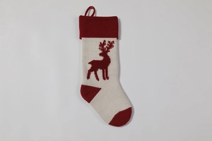 Close-up of beige knitted Christmas stocking with red reindeer pattern and loop