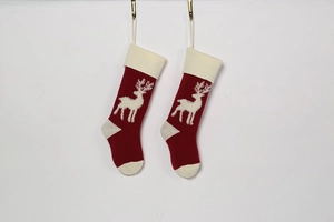 Detail of red knitted Christmas stockings with white reindeer patterns and golden hooks