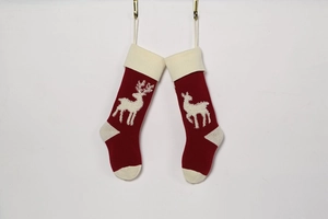Detail of red knit Christmas stockings with 3D elk pattern hanging on brass hooks
