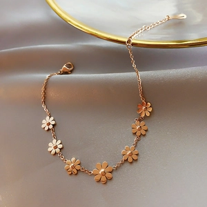 Detail of rose gold daisy charm bracelet with adjustable chain on silk fabric