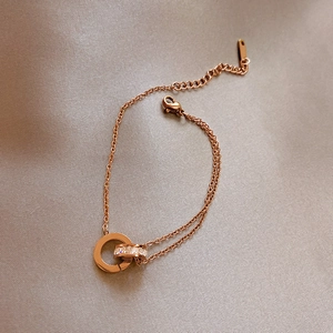 Close-up of rose gold double chain bracelet with micro-paved crystal double ring pendants