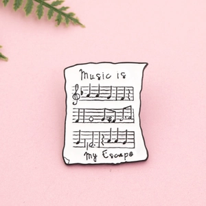 Détail d'un badge émaillé avec partition de musique et texte Music is my Escape